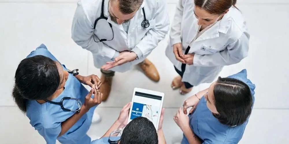 A photo of health care team collaborating in a hospital setting, wearing scrubs and medical equipment.